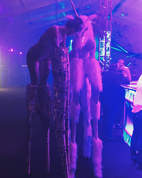Inventive stilt walkers a giraffe and a unicorn graze freely